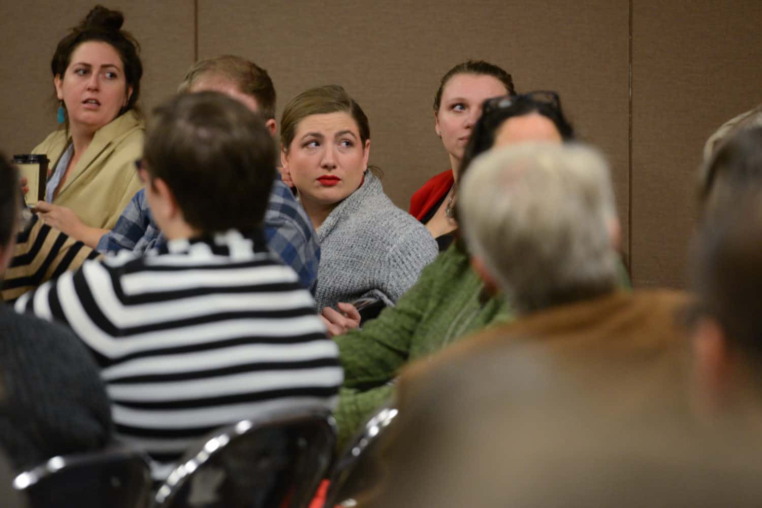 Audience members turn around to face a speaker in a conference panel audience