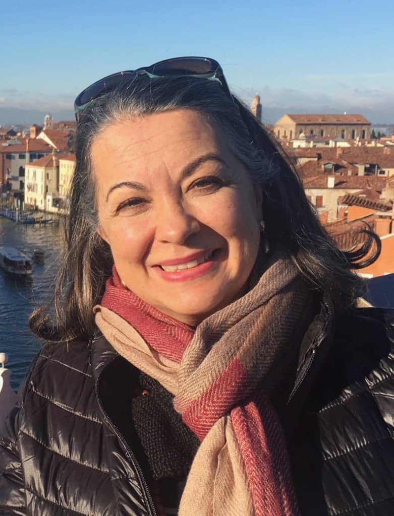 Headshot of a woman, she is smiling at the camera, a scarf around her neck.