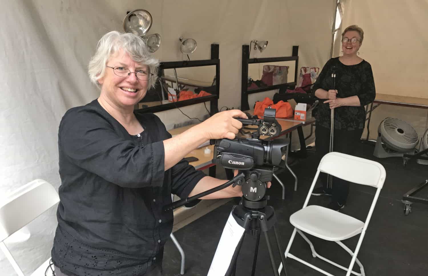 A woman, wearing a black top, smiles at the camera.