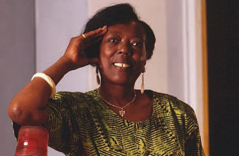 A woman stands leaning on a piece of electronic equipment.