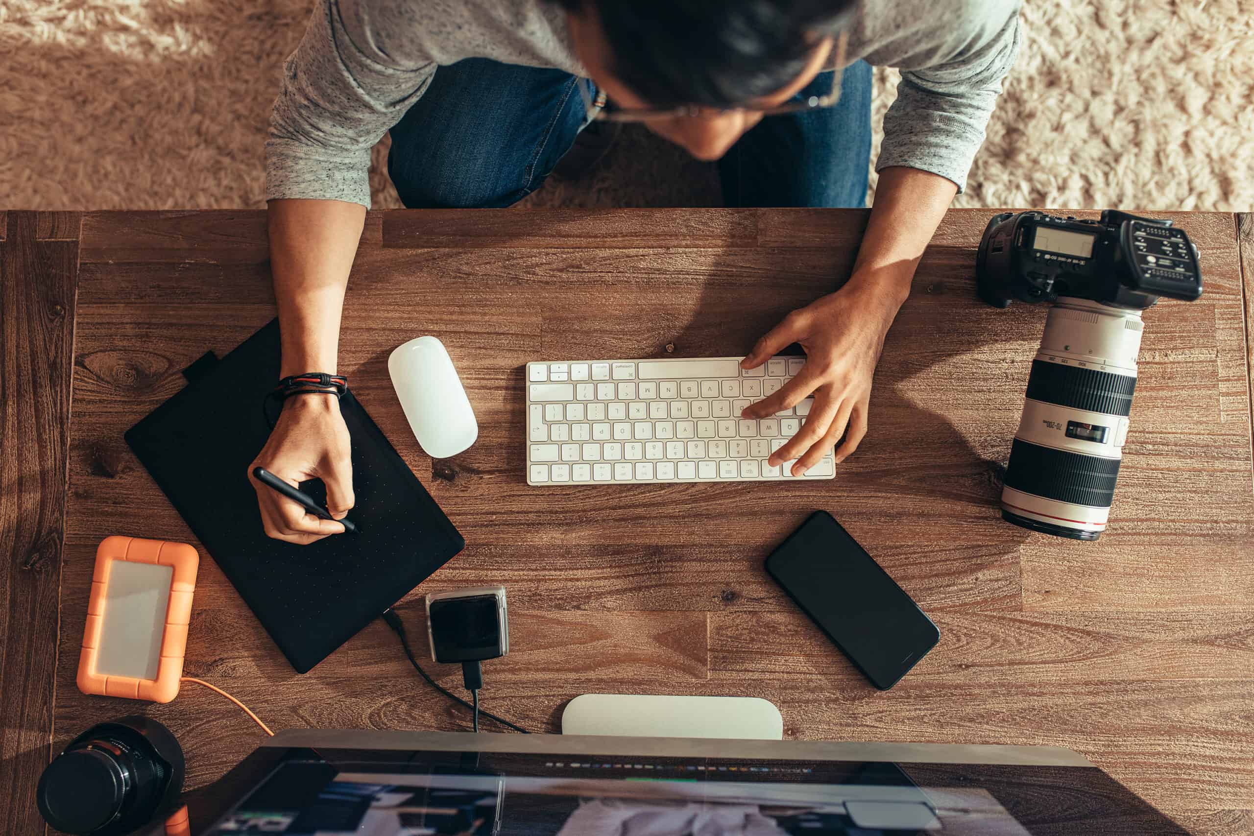 An overhead shot of a person working at a desk, using a digital drawing pad.