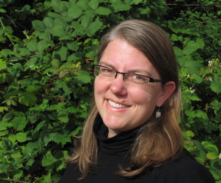 A headshot of a woman in eyeglasses, smiling at the camera.