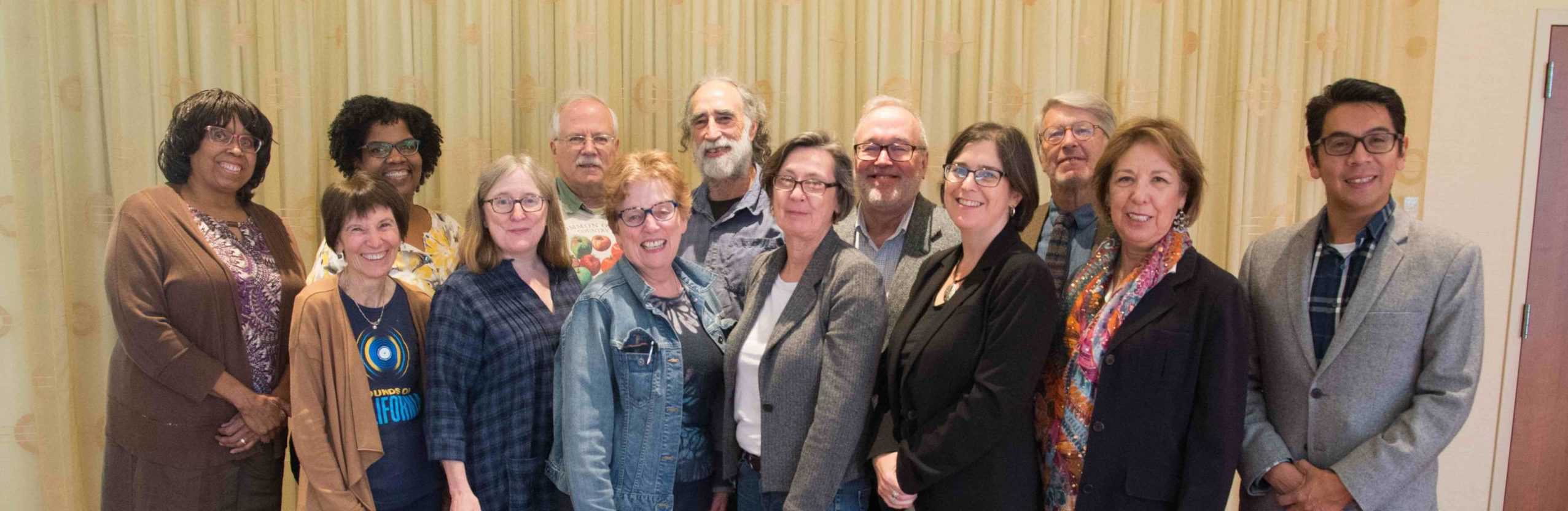 A group of a dozen people smile at the camera.