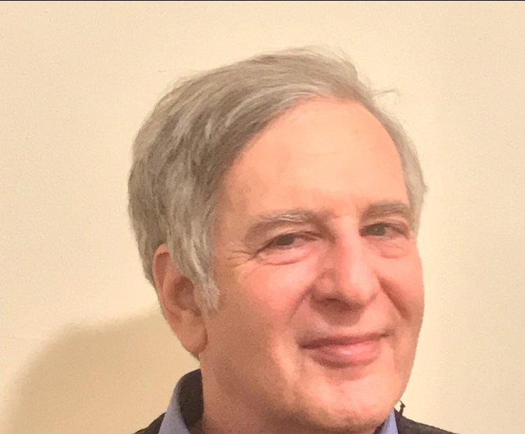 A headshot of a man, looking and smiling at the camera.
