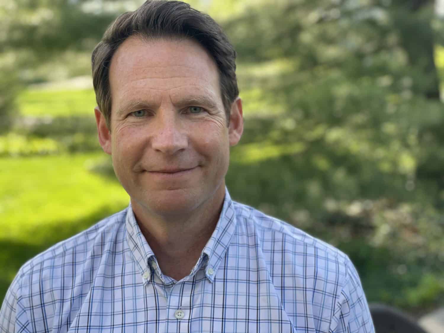 A headshot of a man, smiling at the camera.