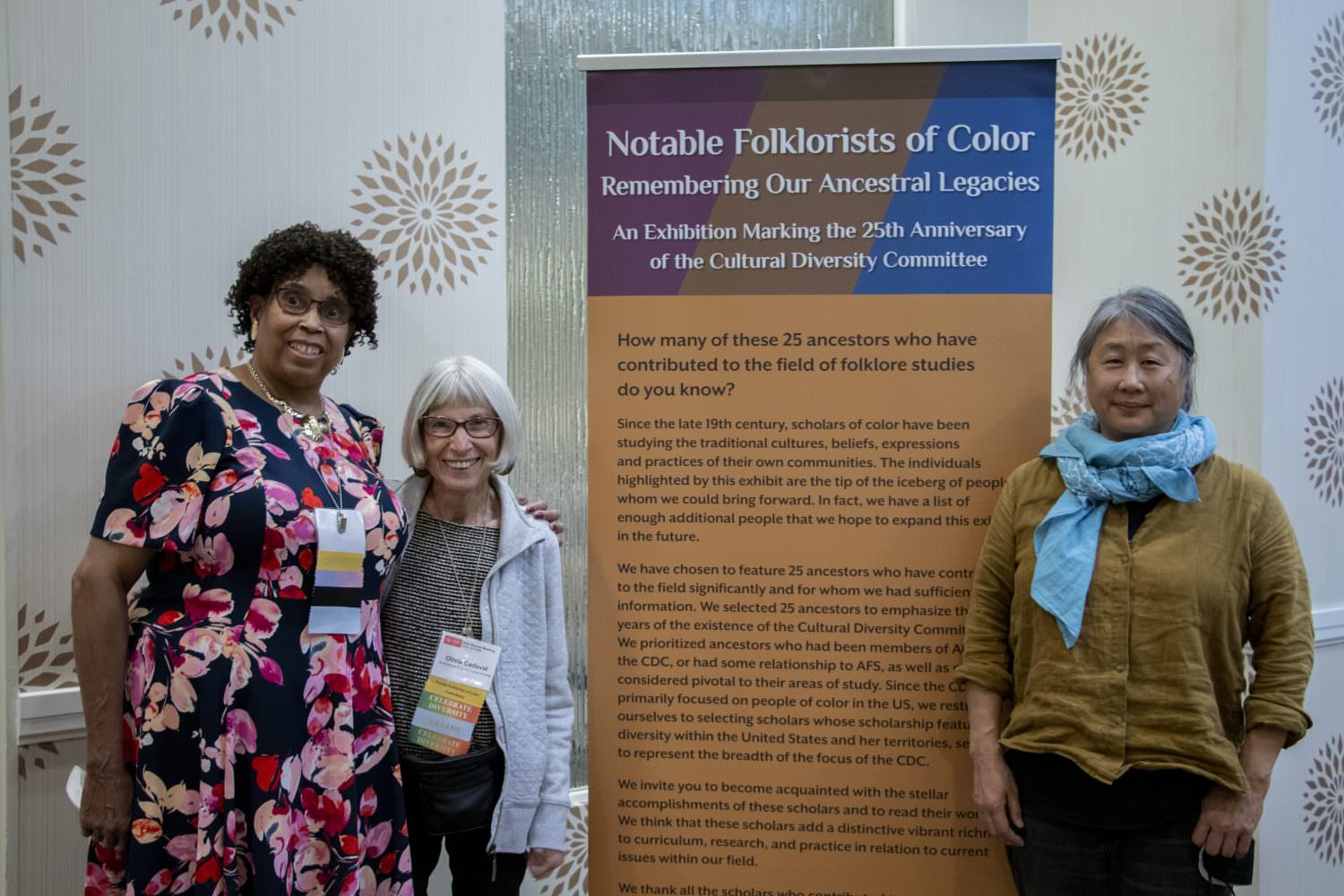 Notable Folklorists of Color curators standing next to the exhibition title banner