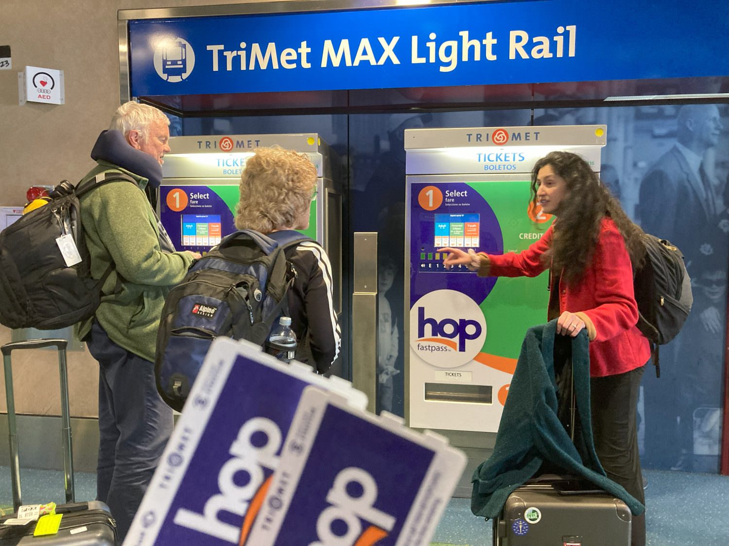 Roz shows an elderly couple how to purchase their hop pass. Two hop pass tickets are shown in the foreground.