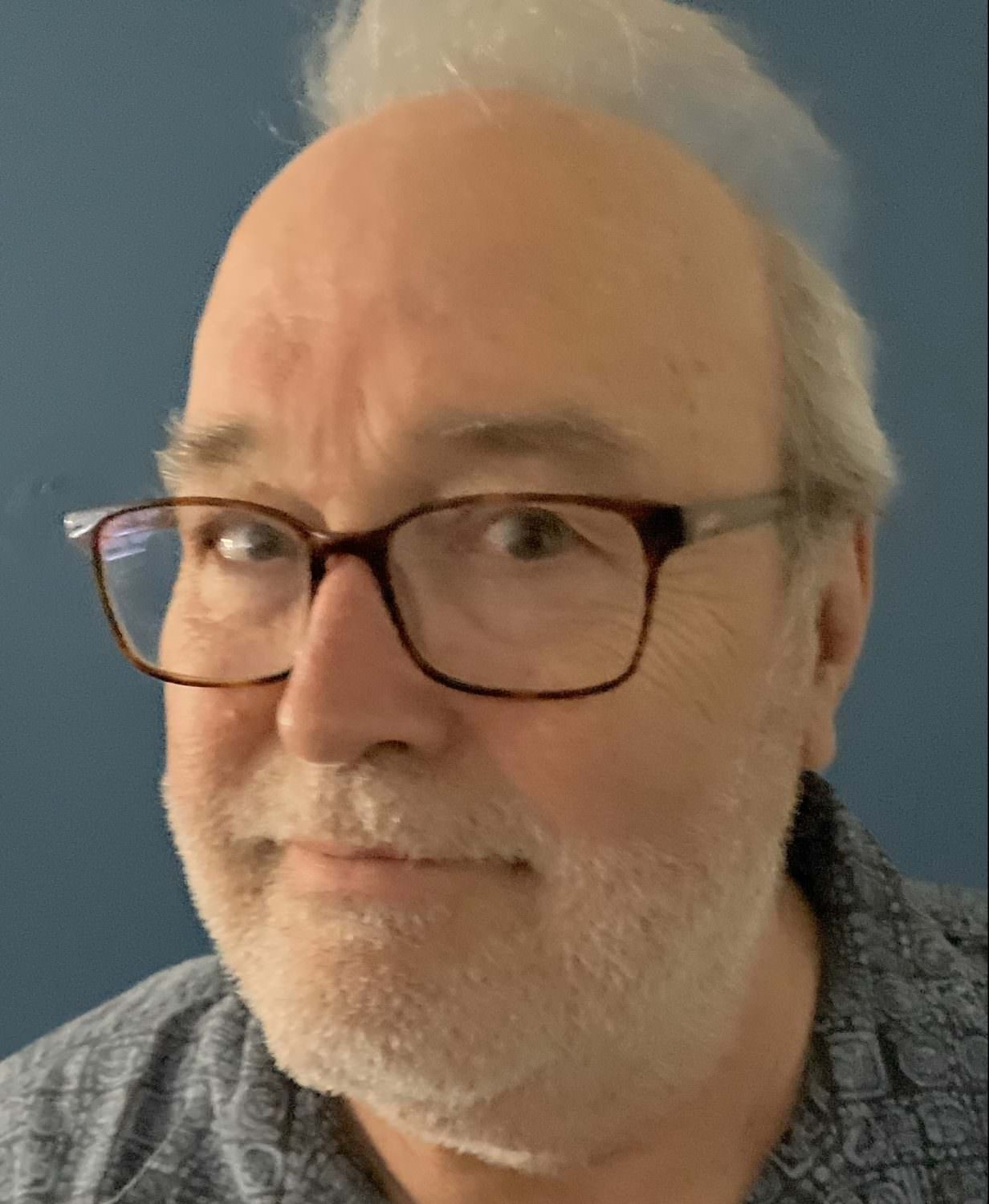 headshot of Tim Lloyd, who wears glasses and has white hair