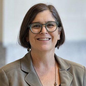 portrait of a smiling white woman with short hair and a pair of glasses