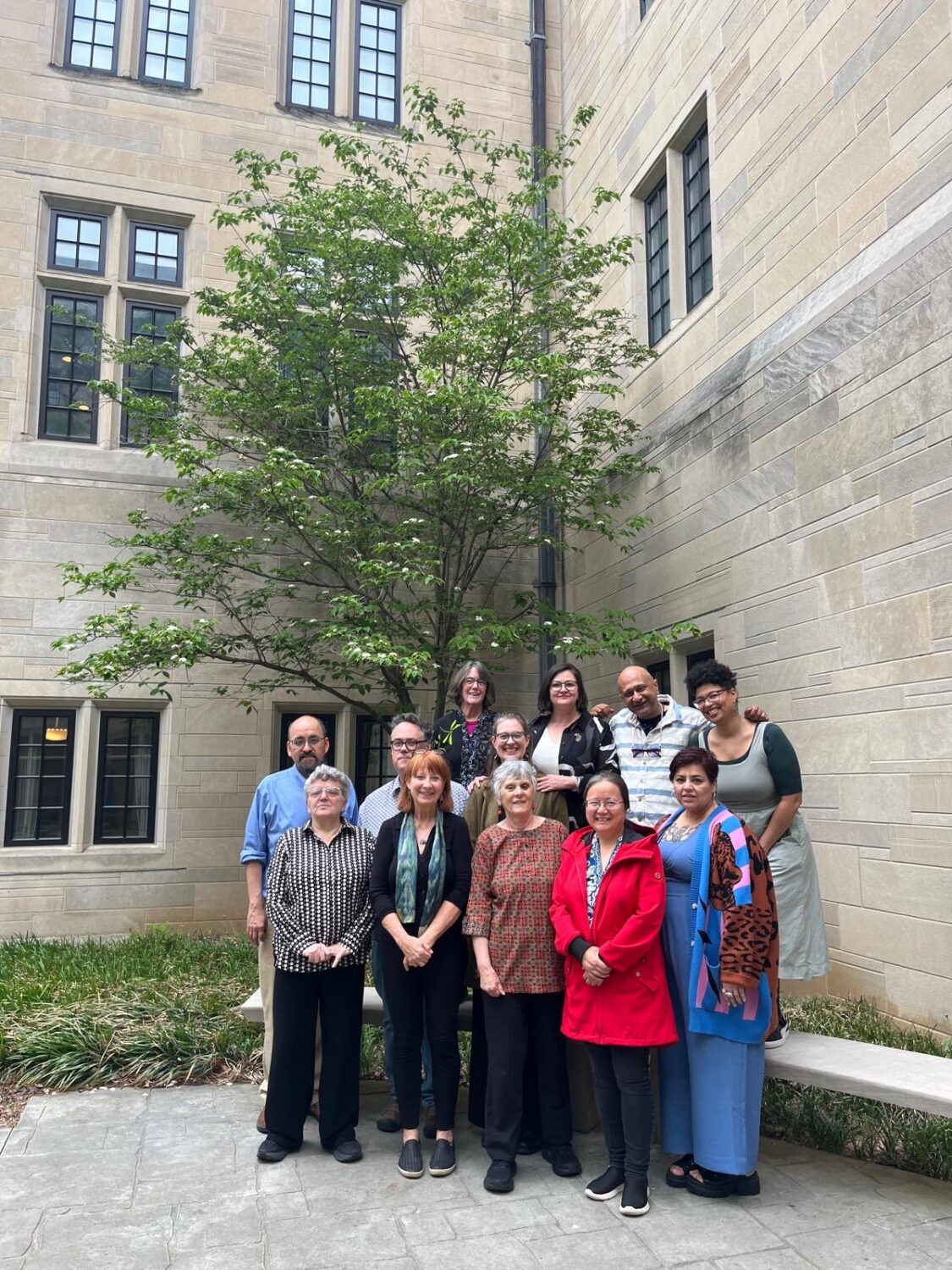 a group of people standing in a courtyard with a large tree